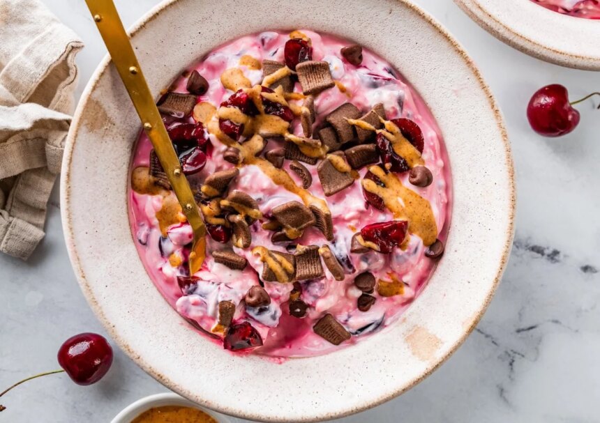 Close-up of chocolate cherry cheesecake yogurt bowl with crunchy toppings.